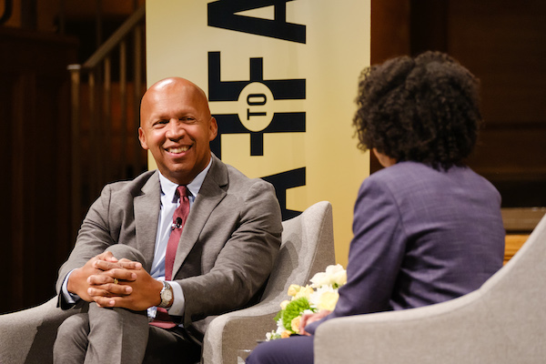Bryan Stevenson (LL.D. '17) sits with legs crossed in conversation at Face To Face event in Wait Chapel. Stevenson is smiling.