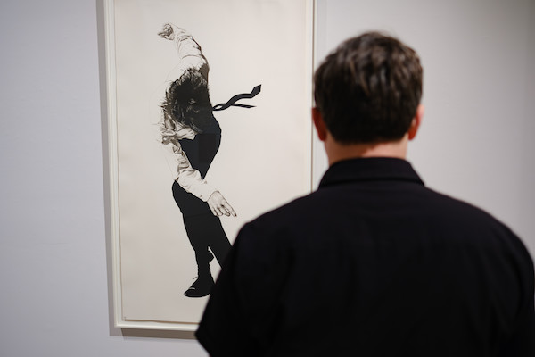 Silhouette of a man observing a black and white piece of art of a man dancing